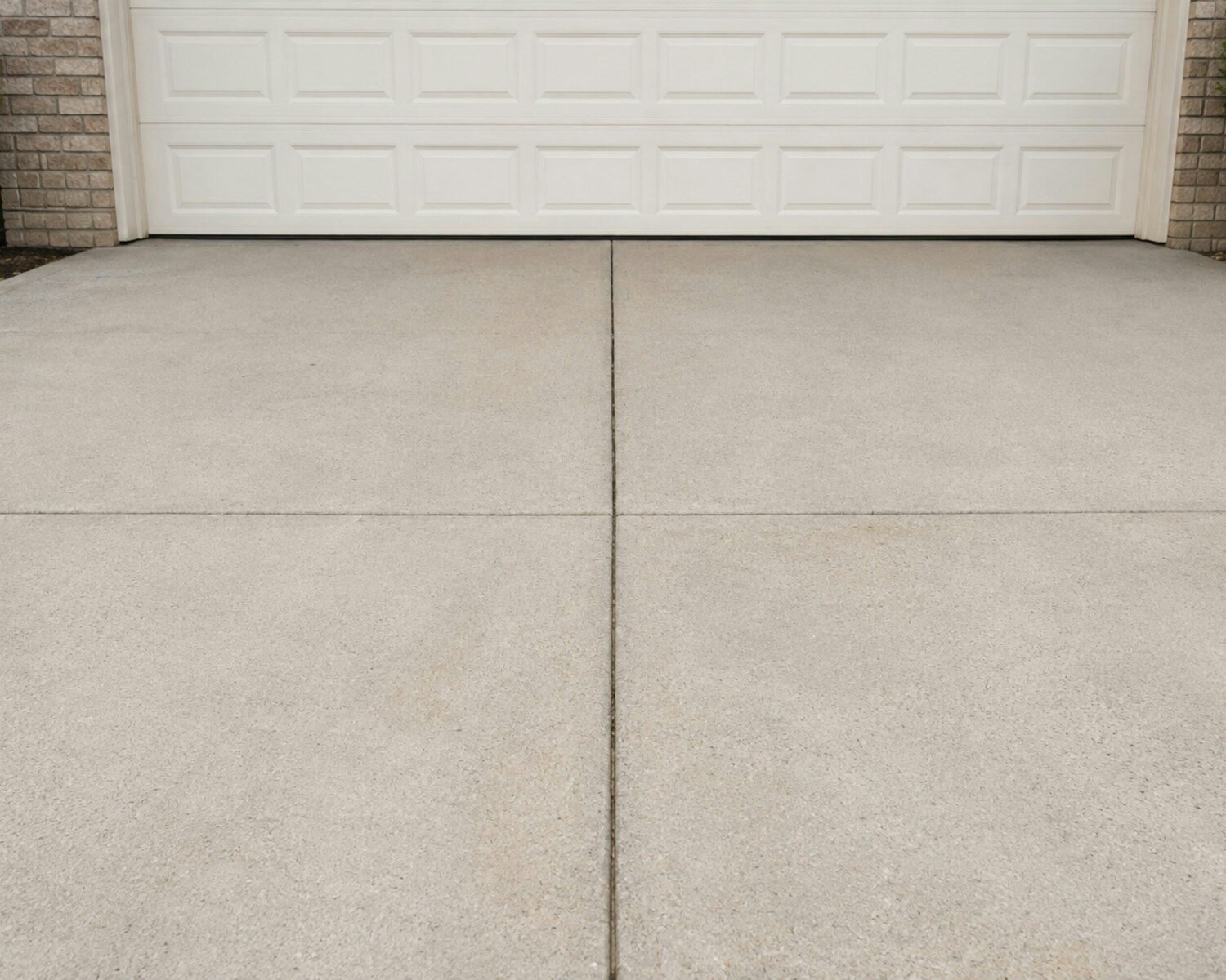 A concrete driveway in front of a white garage door
